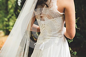Close up of bridal corset. Rear view on bride in white wedding gown with laces. Outdoor photo. Wedding day concept.