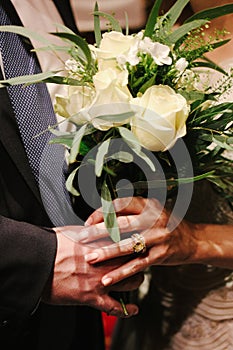 Close-up of bride and groom holding bridal bouquet.