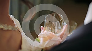Close-up of bride and groom`s hands holding champagne glasses and toasting on wedding day