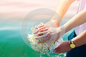 Close-up Bride and groom`s hands with wedding rings and bouquet. Love and marriage. Wedding accessories and decor on the backgrou