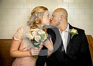 Close up of bride and groom in vintage clothing sitting and touching and kissing