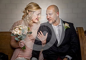 Close up of bride and groom in vintage clothing sitting and touching and talking