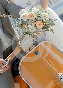 close-up of the bride& x27;s bouquet in the hands of the bride flying on an orange moped. photo