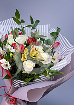 Close up of a bright bouquet of white roses, colored irises and red tulips.