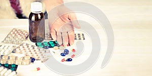 Close-up of bright colored medical pills and capsules with medications and a Woman`s hand next to them. Pills from the first-aid