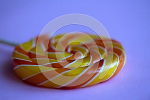 Close up of bright swirl lollipop on purple background