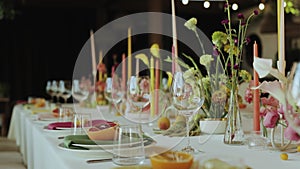 Close-up bright wedding table setting with plates, candles, flowers arrangement for an elegant event in the wedding