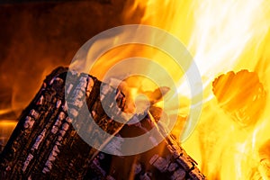 Close up of brightly burning wooden logs with yellow hot flames of fire at night