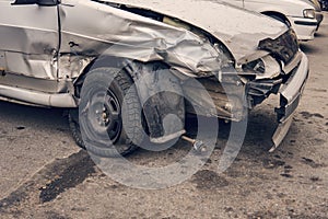 A close up of a broken car after a traffic accident left in the car park. Heavy damage of a bumper and a wheel after a side-on col