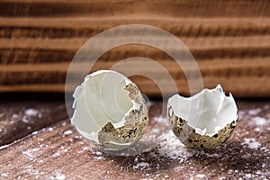 Close up. Broken quail egg shell on the background of brown wooden board. Copy space