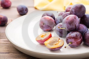 Close-up of a broken ripe blue plum and whole berries on a plate