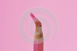 Close-up of broken tip of pink colored pencil on pink background - Concept of violence against women