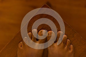 Close up of a brown asian feet,  on a brown wooden background  with Mortons toe. photo