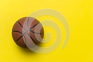 Close up of brown basketball ball isolated on yellow. Sport team concept. Top view, space for your text