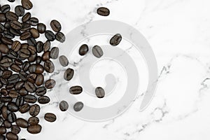 Close up, brown coffee beans on a marble pattern background with copy space. Top view