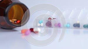 Close up brown drug bottle with colorful capsules of antibiotic, isolated in white background with Pill box daily take a medicine,