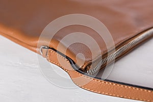 Close up of brown leather bag with zipper on grunge white wooden board