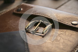 Close up of brown leather handmade handbag with bronze clasp on wooden table