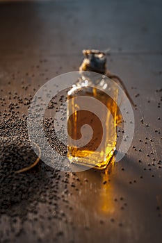 Close up of brown mustard seed,with its extracted oil on a brown wooden surface in dark Gothic colors.Its oil Boosts Cardiac Healt