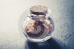 Close-Up Of A Brown Raw Sugar In A Small Glass Bottle Closed With A Cork Stopper On Slate Stone