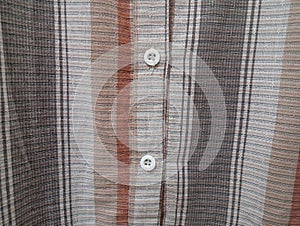 Close-up of a brown shirt\'s buttoned, emphasizing the fabric\'s texture and sewing precision.