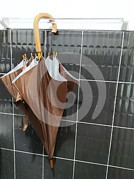 Close-up of brown umbrellas, white hanging rails, black wall, brown umbrella and black wall