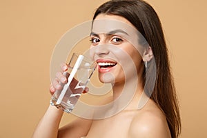 Close up brunette half naked woman 20s with perfect skin nude make up glass water isolated on beige pastel wall