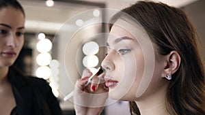Close-up of brunette woman applying cosmetic on cheekbones with a make up brush. Girl in the salon make-up, apply powder
