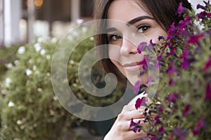 Close up of brunette woman face in flowers. She smiling cheerfully. Copy space