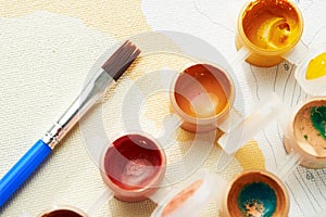 Close up brush and jars with multi-colored acrylic paint for painting by numbers. Top view