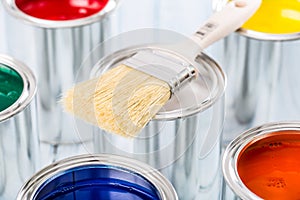 Close-up brush lying on multicolored paint cans