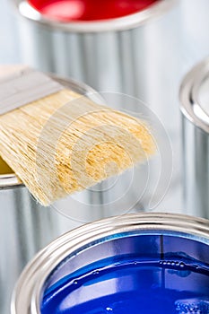 Close-up brush lying on multicolored paint cans