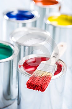 Close-up brush with red color lying on paint can