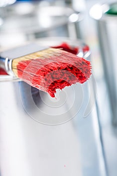 Close-up brush with red color lying on paint can