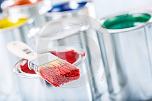 Close-up brush with red color lying on paint can