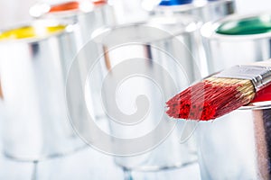 Close-up brush with red color lying on paint can