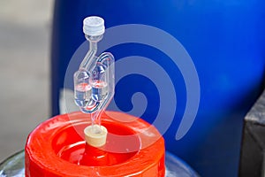 Close-up of a bubbling airlock on fermentation container. Rubber Stopper for a glass carboy. Process of making home beer from malt