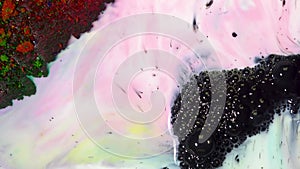 Close-up of bubbling black ink. On colorful surface of milk with paint stains appears bubbly black ink. Bubbling black