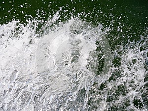 Close-up of bubbling water from the wake of a boat against a dark background