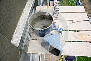A close-up on a bucket with mortar, pvc plaster sprayer machine, stucco concrete sprayer gun, working tools of a building