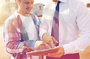 Close up of builder and businessman with tablet pc