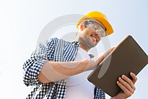 Close up of builder in hardhat with tablet pc
