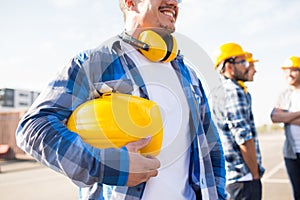 Close up of builder holding hardhat at building