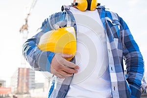 Close up of builder holding hardhat on building