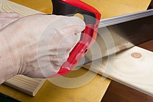 Close up of builders with arm saw sawing board