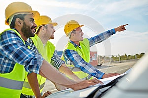 Close up of builders with blueprint on car hood