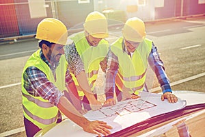 Close up of builders with blueprint on car hood