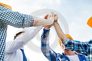 Close up of builders in hardhats making high five