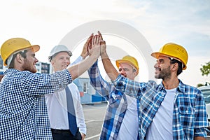 Close up of builders in hardhats making high five