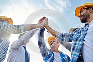 Close up of builders in hardhats making high five